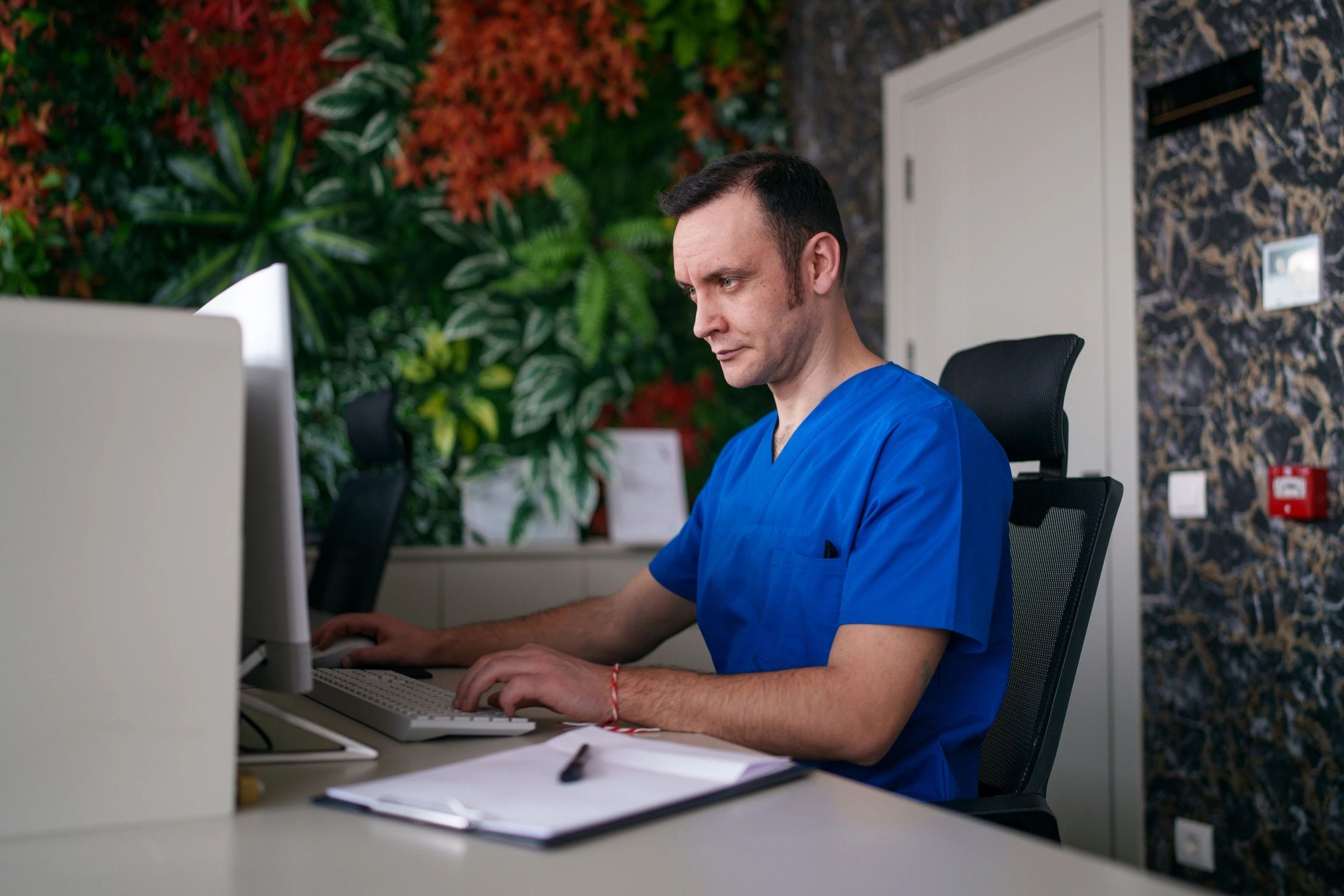 Healthcare worker using computer at a clinic reception desk